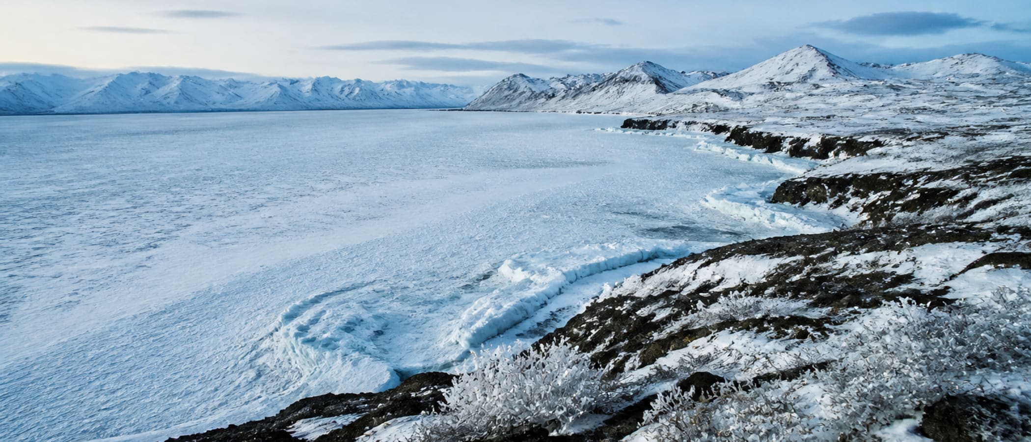 Arctic snowfield and ice under pale winter light, the cold survival environment where staying dry decides everything